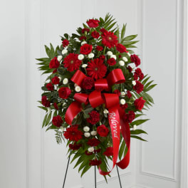 Red floral standing spray with a large ribbon on an easel