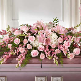 Pink roses and lilies arranged across a casket
