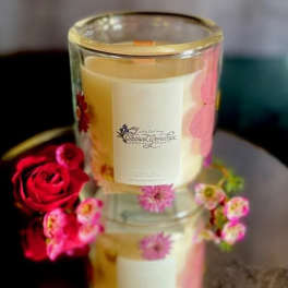 Glass candle with floral decoration beside a red rose