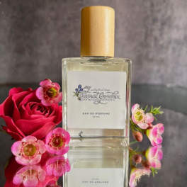 Perfume bottle beside a red rose and small pink flowers