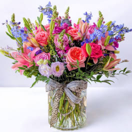 Colorful mixed bouquet in a clear glass vase with a patterned ribbon