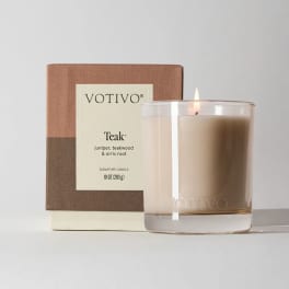 Lit scented candle in a glass jar with its box