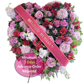 Heart-shaped floral tribute with a "Beloved Husband" sash