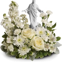 White floral arrangement with a small religious statue in the center