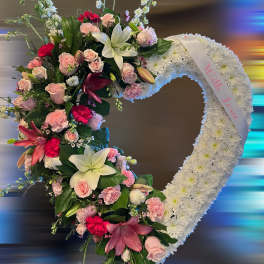Open heart wreath of white flowers with pink roses, lilies, and carnations and a ‘With Love’ ribbon