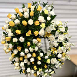 Standing open-circle wreath of white and yellow flowers on an easel