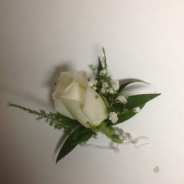 White rose boutonniere with baby's breath and green leaves