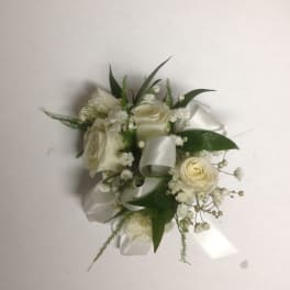 White rose corsage with satin ribbon and greenery