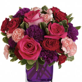 Bouquet of pink, red, and purple flowers in a purple glass vase