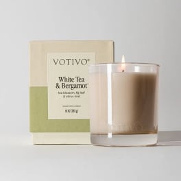 Lit white tea and bergamot candle beside its box