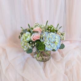 Pink roses and blue hydrangeas in a glass vase