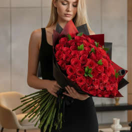 Woman holding a large bouquet of red roses wrapped in black and red paper