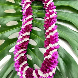 Purple and white flower lei on large tropical leaves