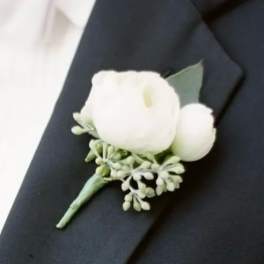 White boutonniere with small greenery on a dark suit lapel