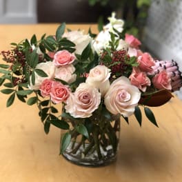 Pink and white roses arranged in a glass vase with greenery