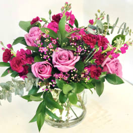Pink roses and magenta carnations in a clear glass vase