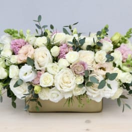Low floral arrangement of white and blush roses in a rectangular vase