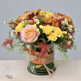 Mixed bouquet of roses and daisies in a glass vase with twine wrap