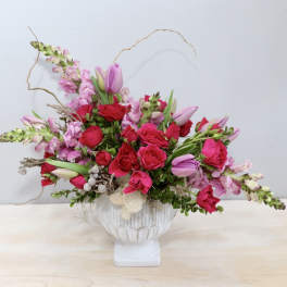 Pink and red floral arrangement in a white vase