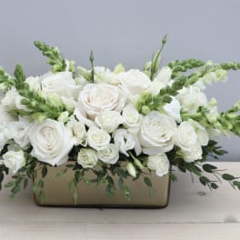 White roses and snapdragons arranged in a rectangular vase