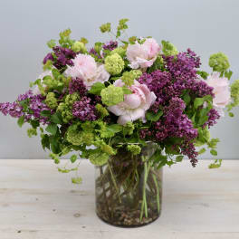 Pink peonies and purple lilacs in a clear glass vase