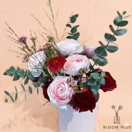 Bouquet of pink and red flowers in a white container
