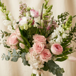 Tall hand-tied bouquet of pale pink roses, tulips, and white flowers tied with a ribbon
