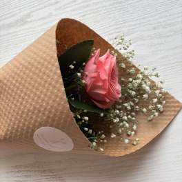Single pink rose wrapped in brown paper with baby's breath
