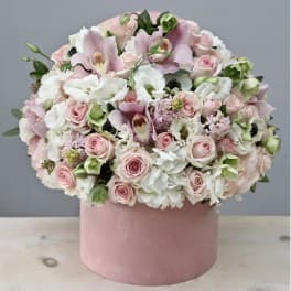 Pink and white flower arrangement in a round pink box