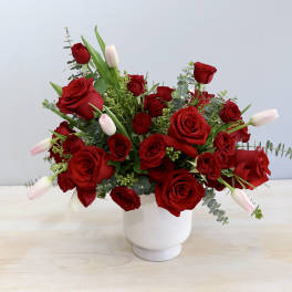 Red roses and pale tulips arranged in a white vase