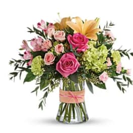 Pink roses and lilies arranged in a clear glass vase