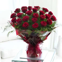 Bouquet of red roses wrapped in burgundy paper with a ribbon