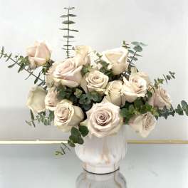 Cream rose bouquet in a white vase with eucalyptus