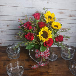 Bouquet of red roses and yellow sunflowers in a glass vase with ribbon