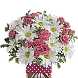 Pink roses and white daisies in a square glass vase with a polka-dot wrap
