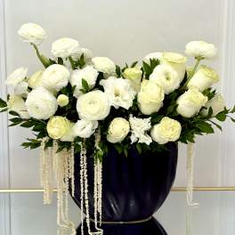 White floral arrangement in a dark vase with trailing white strands