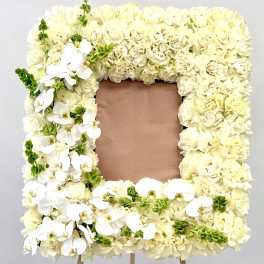 Square floral frame of cream roses and white orchids on an easel