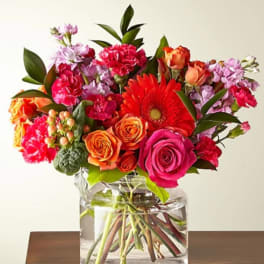 Bright mixed bouquet in a clear glass vase with roses and gerbera daisies