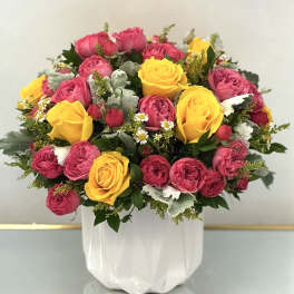 Pink and yellow rose bouquet in a white vase