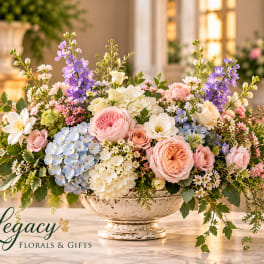 Pastel floral arrangement in a white pedestal bowl with roses and hydrangeas