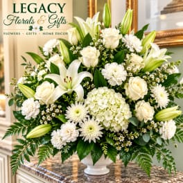 White lilies, roses, and mums arranged in a white vase