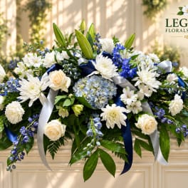 White and blue floral arrangement with roses, lilies, and ribbons