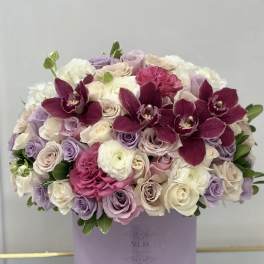 Lavender and white rose bouquet with deep magenta orchids in a round box