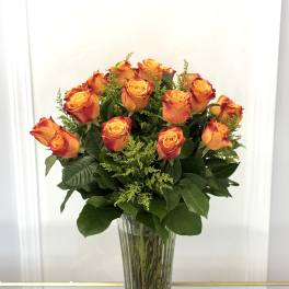 Orange roses arranged in a tall clear glass vase