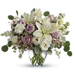 Lavender roses and white lilies in a clear glass vase