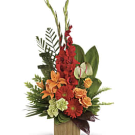 Tropical arrangement with red, orange, and green flowers in a wooden container