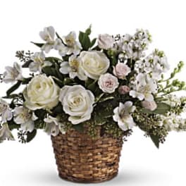 White roses and pale flowers in a woven basket