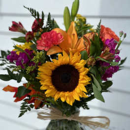 Mixed bouquet with a sunflower and orange lily in a glass vase