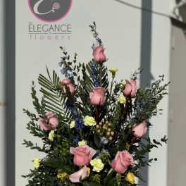 Tall arrangement of pink roses and mixed accent flowers in a vase