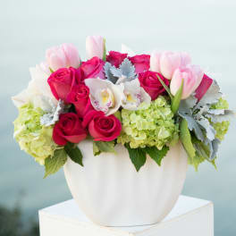 Pink roses and tulips arranged in a white vase